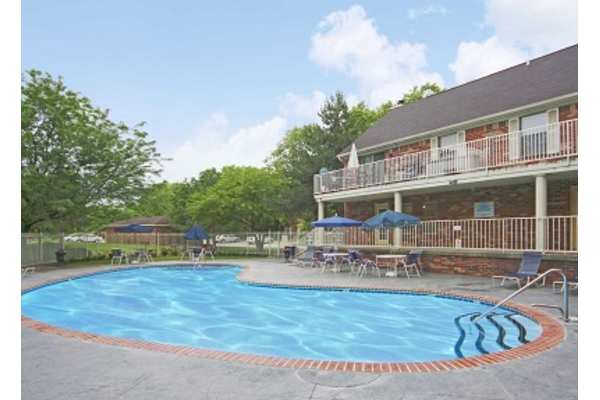 A large outdoor swimming pool surrounded by a patio area with chairs and umbrellas.